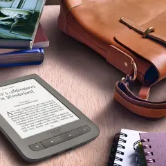Une liseuse pour malvoyant affiche "Alice au pays des merveilles" à côté d'un sac en cuir et de livres.