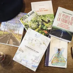 Un béret, un verre de vin, une baguette et plusieurs livres sur la France, dont "Voyages en France" et "La Diagonale du vide", parfaits pour un récit de voyage.