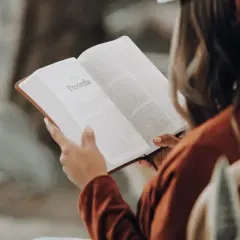 Une influenceuse littéraire lit le livre des Proverbes, absorbant la sagesse ancienne.