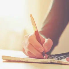 Main d'une personne écrivant dans un carnet. Une histoire vraie prend forme, un témoignage précieux consigné dans ce livre.