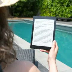 Une personne lit un livre électronique Kobo au bord d'une piscine, profitant du soleil. Un excellent choix pour un epub reader sur Ubuntu.