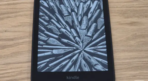 Une liseuse Kindle affiche une image abstraite de plumes d'encre. Parfait pour une pause thé et lecture.