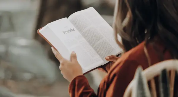 Une influenceuse littéraire lit le livre des Proverbes, absorbant la sagesse ancienne.