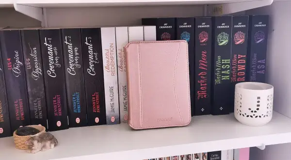 Une liseuse Kobo rose est bloquée en veille, posée sur une étagère remplie de livres.