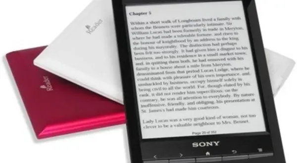 Une liseuse Sony noire affiche un extrait de roman. Deux autres liseuses, une blanche et une rouge, sont empilées derrière.