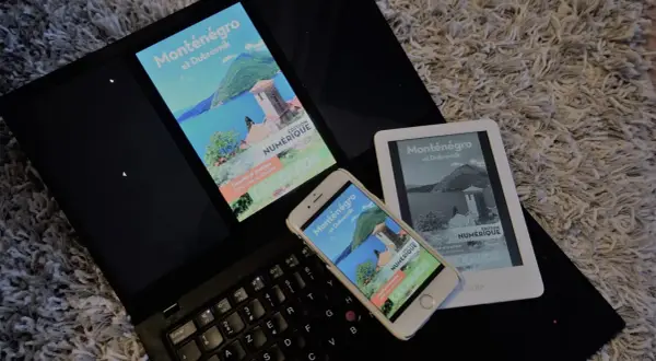 Un ordinateur portable, un smartphone et un **kindle audio** affichent un guide numérique sur le Monténégro et Dubrovnik.