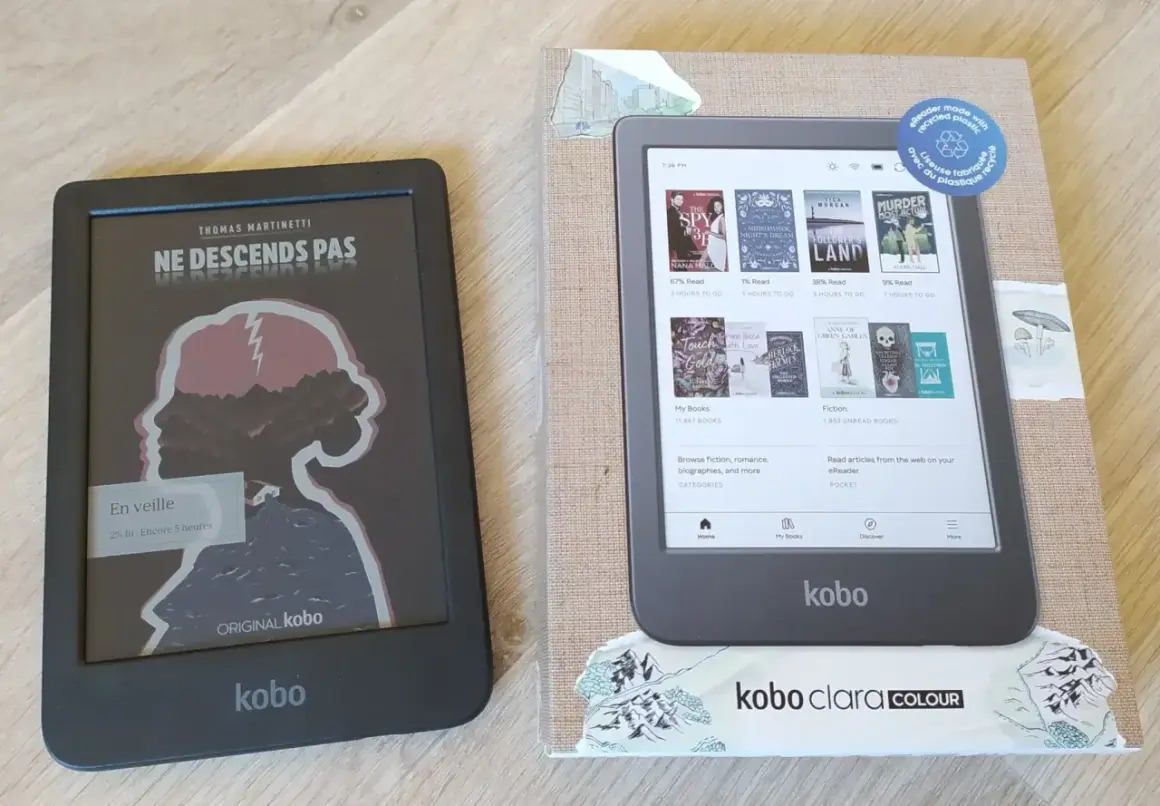Deux liseuses Kobo, dont une Kobo Clara Colour, sur un fond en bois. L'une affiche une couverture de livre, l'autre l'écran d'accueil.