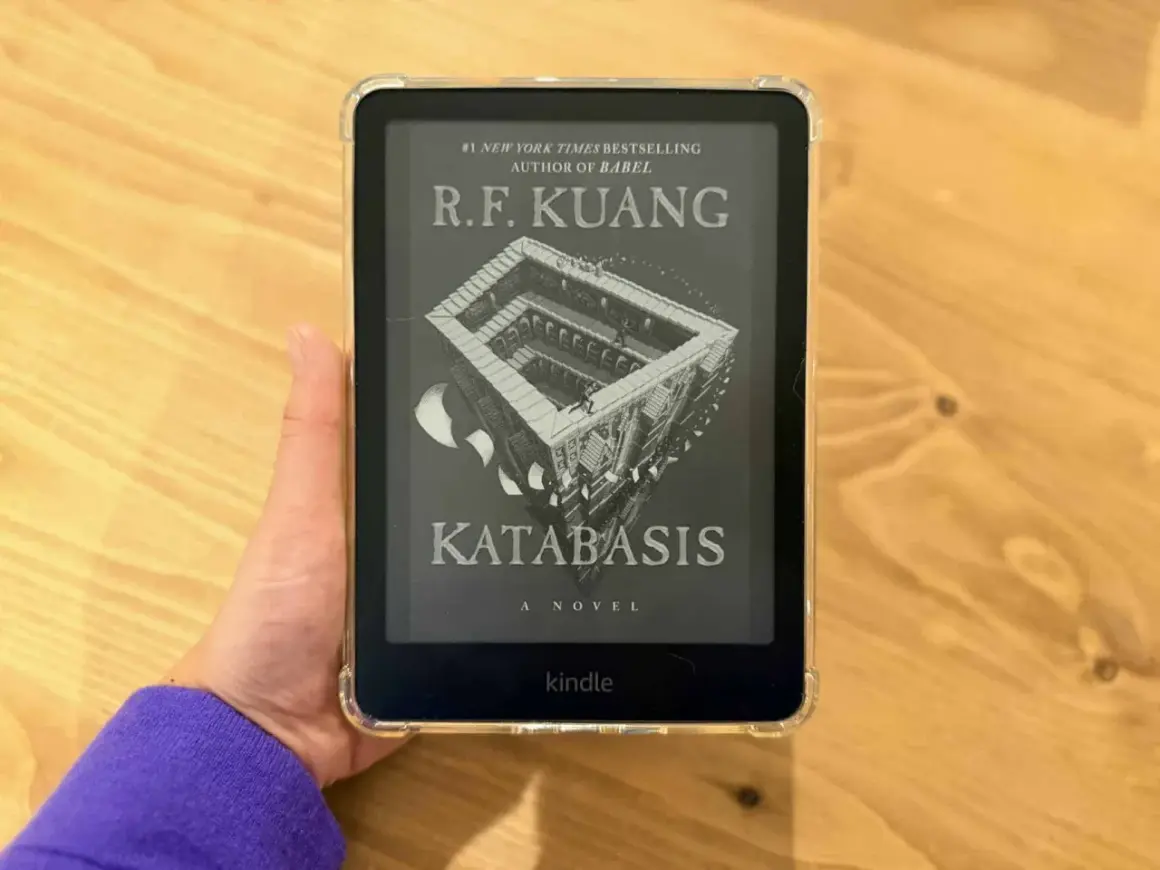 Main d'une personne tenant un Kindle Paperwhite affichant la couverture du livre "Katabasis" de R.F. Kuang.