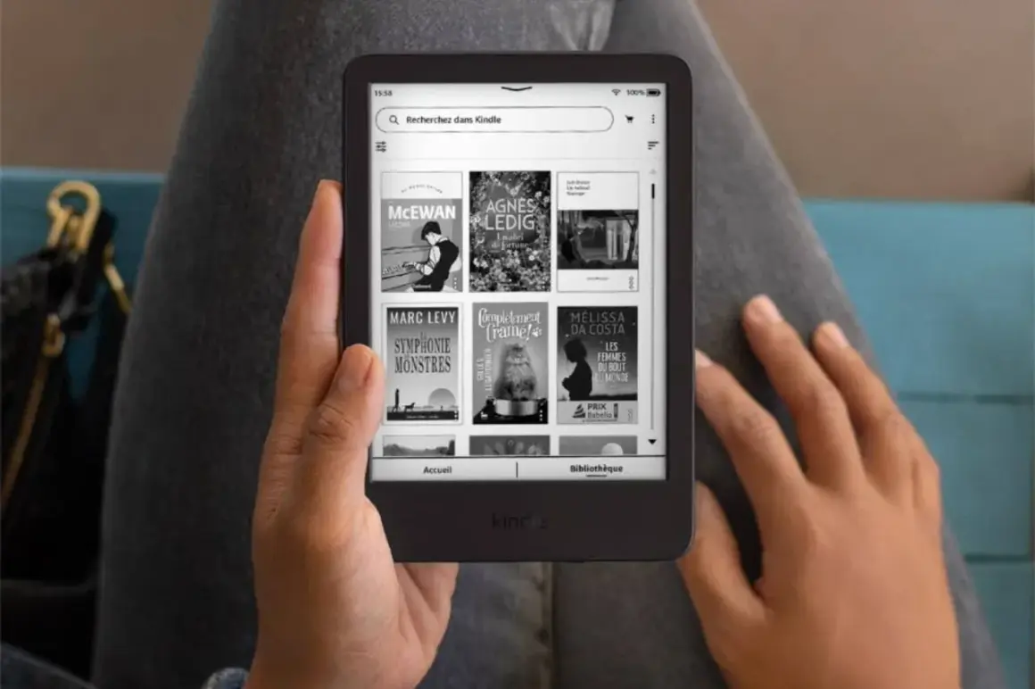 Une personne tient un Kindle affichant des livres, une invitation à découvrir un livre Kindle gratuit.