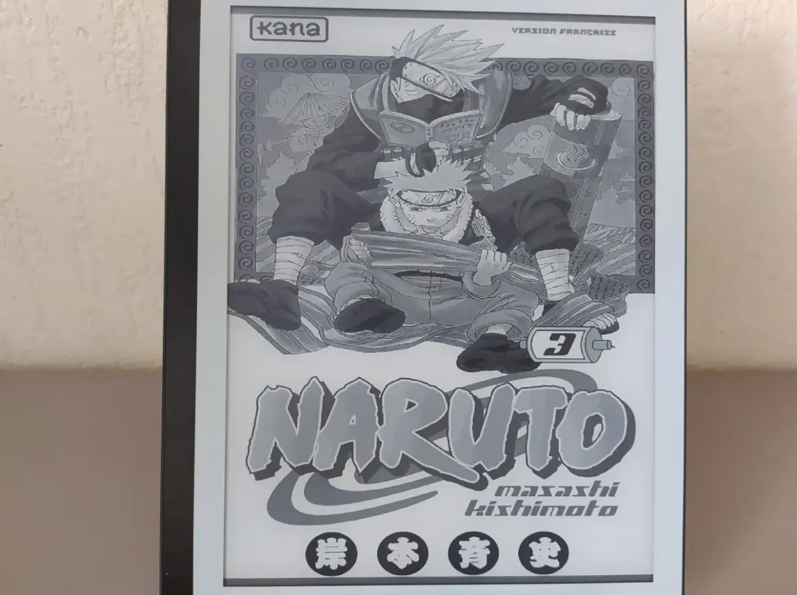 Un **manga sur liseuse** affiche la couverture du tome 3 de Naruto, avec Kakashi lisant par-dessus Naruto.