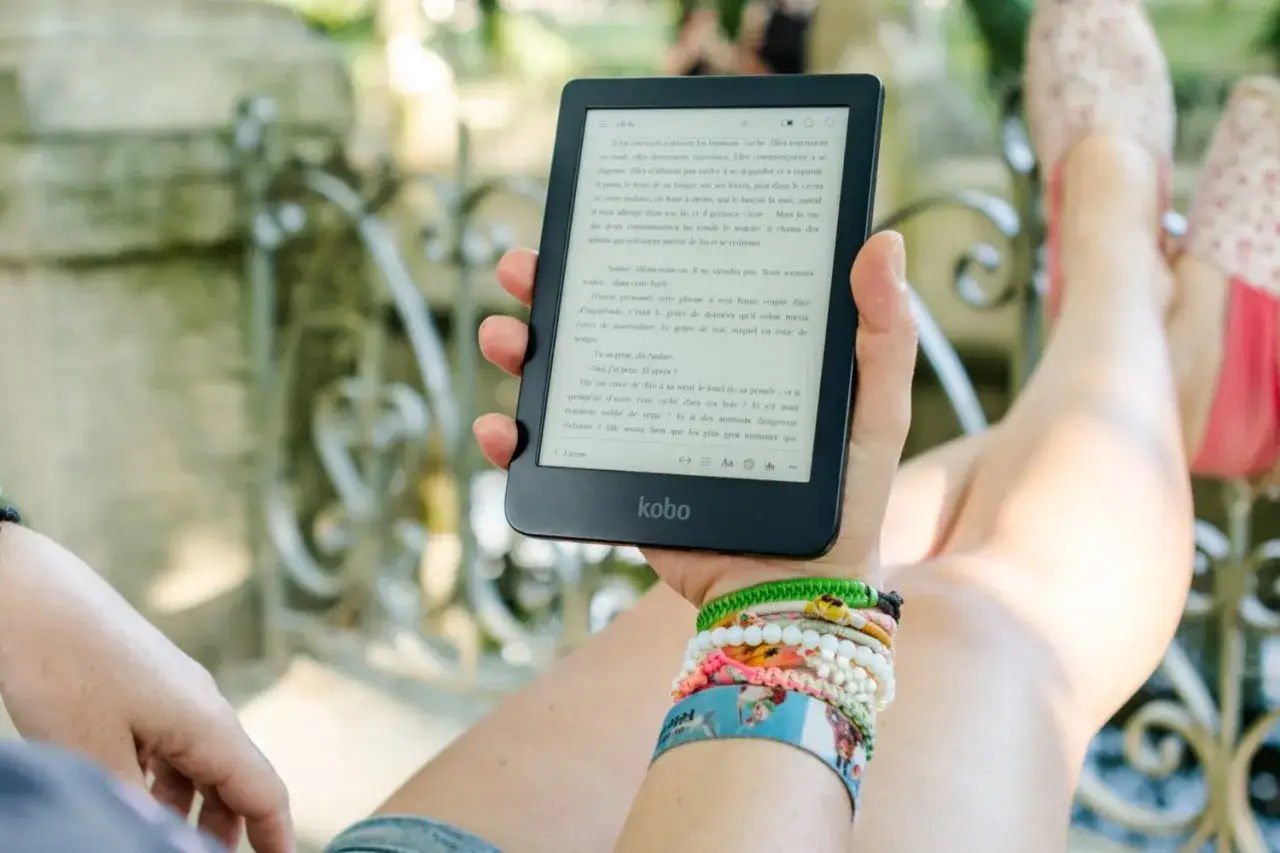 Une personne lit un livre sur tablette, profitant d'un moment de détente en plein air. Une belle façon de lire un livre sur tablette gratuit.
