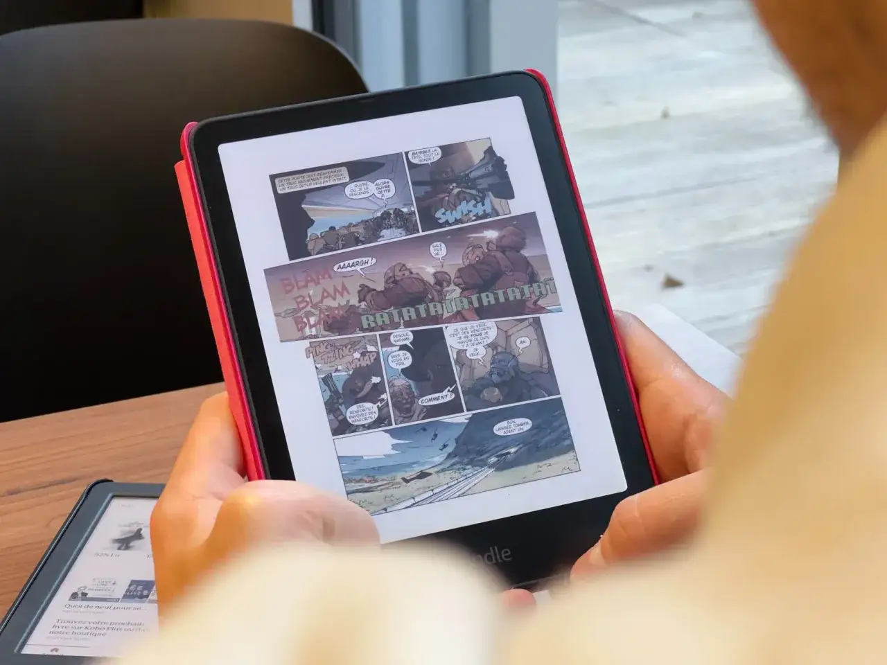 Une personne lit une bande dessin&eacute;e d'action sur sa liseuse Kindle. Les bulles de dialogue 