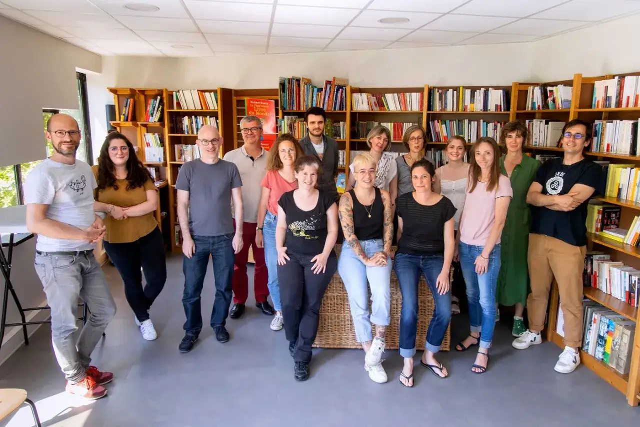 Une &eacute;quipe souriante pose devant des &eacute;tag&egrave;res remplies de livres pour adolescents.