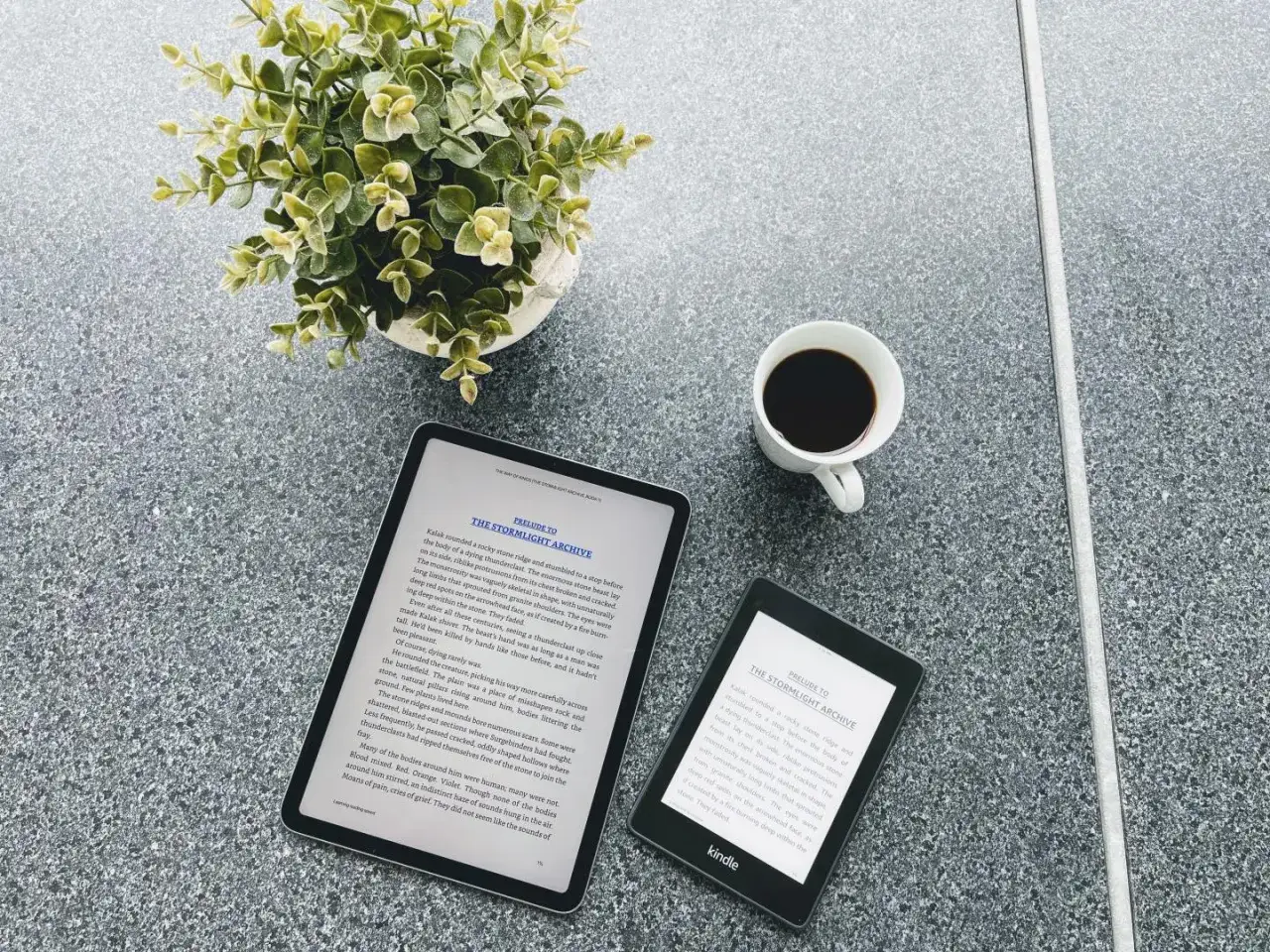 Une tasse de caf&eacute;, une plante verte et un appareil Nextory Kindle &agrave; c&ocirc;t&eacute; d'une tablette affichant un livre.