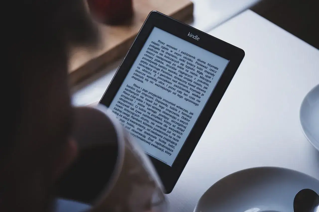 Une personne lit sur une liseuse Kindle. Apprenez comment pr&ecirc;ter un livre Kindle pour partager vos lectures.