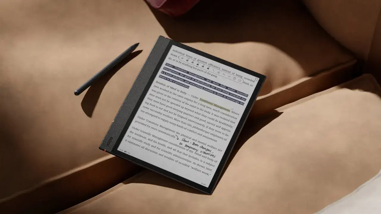 Une liseuse avec un stylet repose sur un canapé. Les yeux du lecteur sont concentrés sur le texte, absorbés par la lecture.