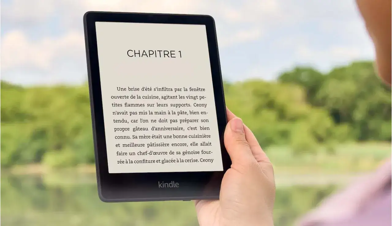 Main tenant un Kindle Paperwhite, lisant un livre en français. Un guide d'utilisation Kindle Paperwhite français serait utile pour explorer toutes ses fonctionnalités.