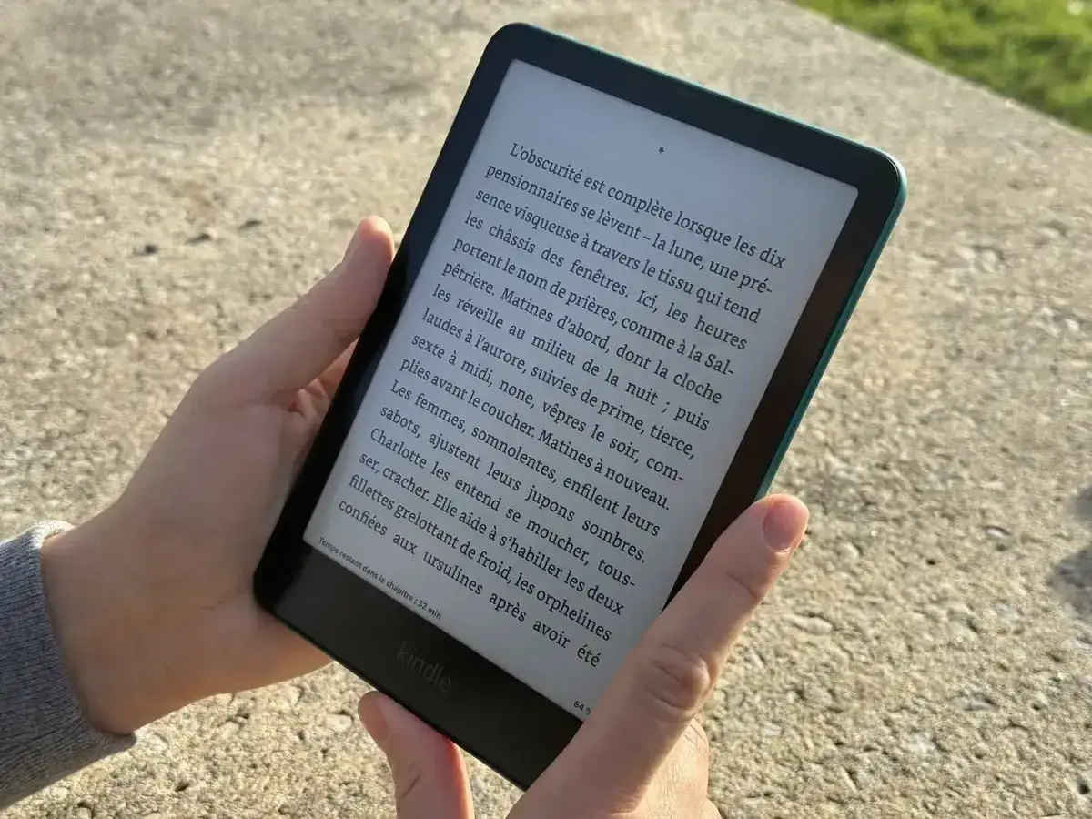 Main tenant une liseuse Kindle, lisant un livre protégé par adobe drm.