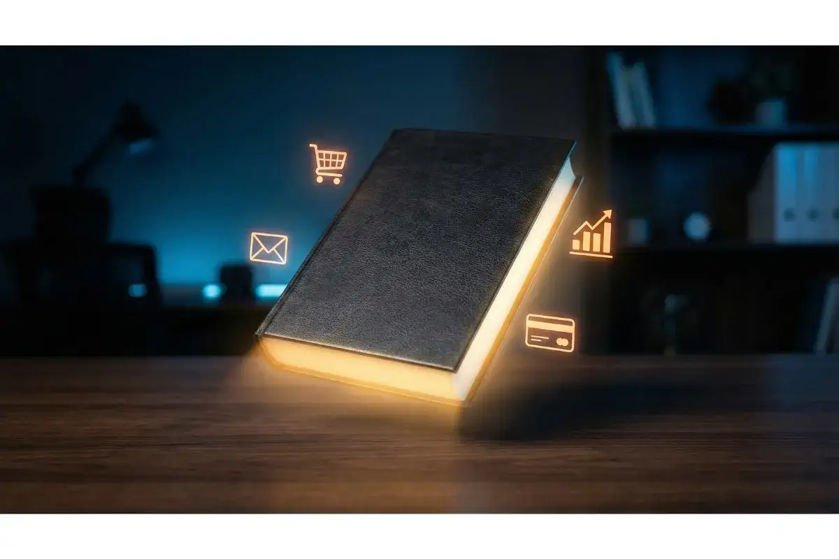 Un livre noir lumineux sur un bureau, entour&eacute; d'ic&ocirc;nes de commerce &eacute;lectronique. Le prix de cet ebook est une invitation &agrave; la r&eacute;ussite.