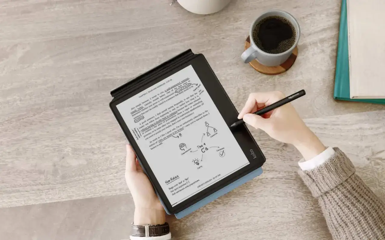 R&eacute;sum&eacute; d'un livre sur une liseuse, avec une tasse de caf&eacute; et un stylet. La personne prend des notes sur le texte.