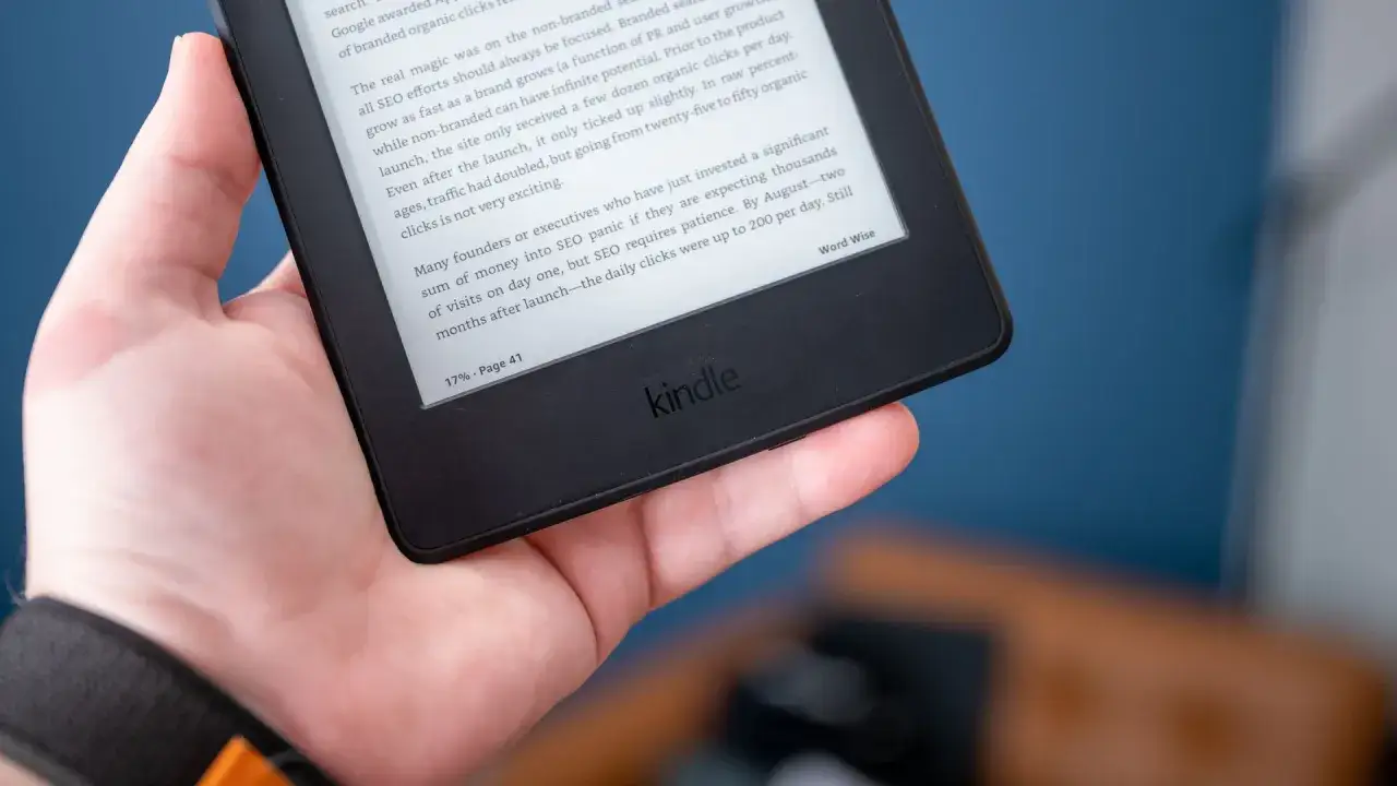 Une main tient une tablette ou liseuse Kindle affichant un texte sur le référencement.