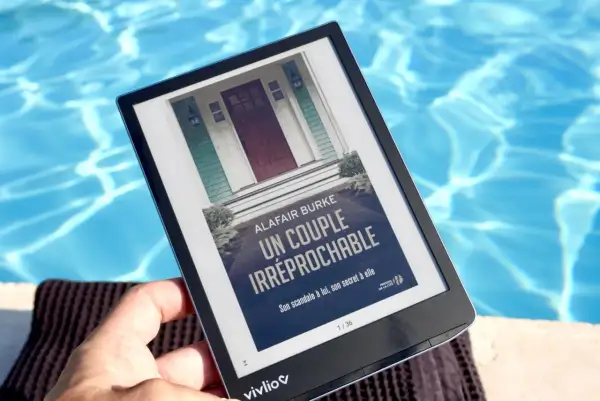 Une liseuse e-ink affiche "Un couple irréprochable" au bord d'une piscine.