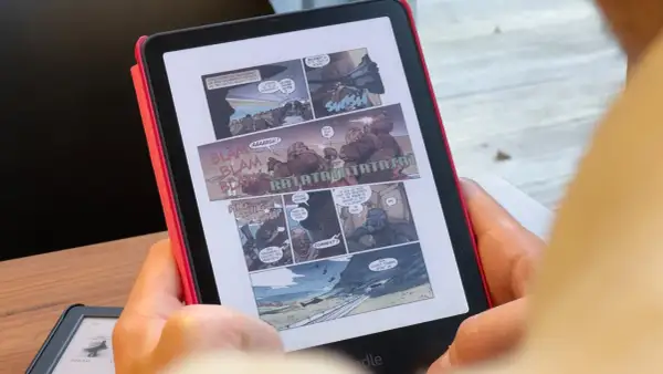 Une personne lit une bande dessinée d'action sur un cbz kindle. Des onomatopées comme "BLAM" et "RATATATA" parsèment les cases.