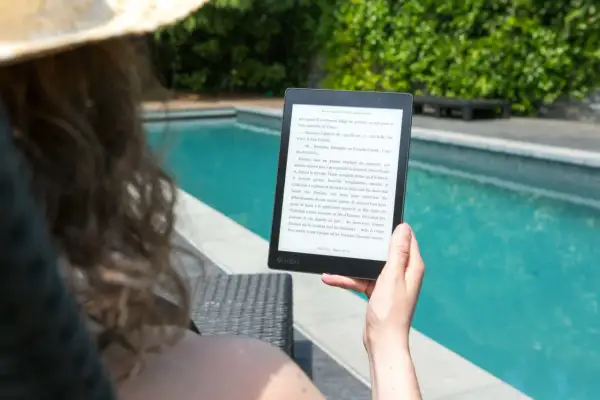 Une personne lit un livre électronique Kobo au bord d'une piscine, profitant du soleil. Un excellent choix pour un epub reader sur Ubuntu.